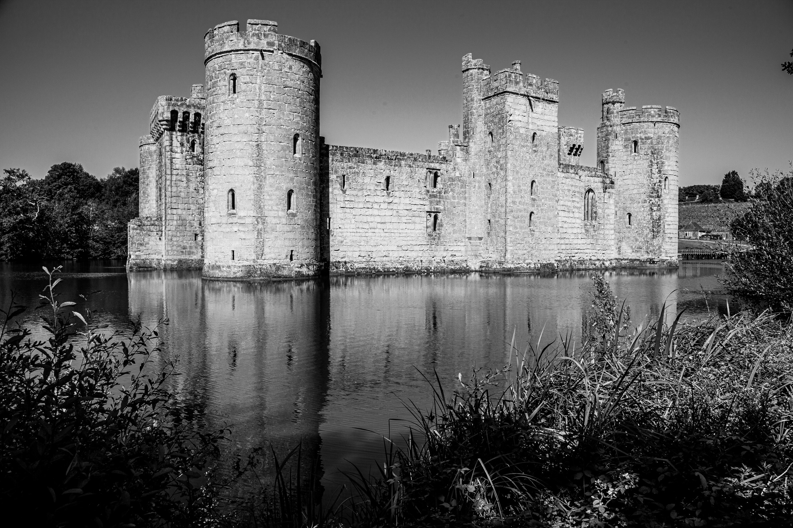 grayscale photo of concrete building near body of water